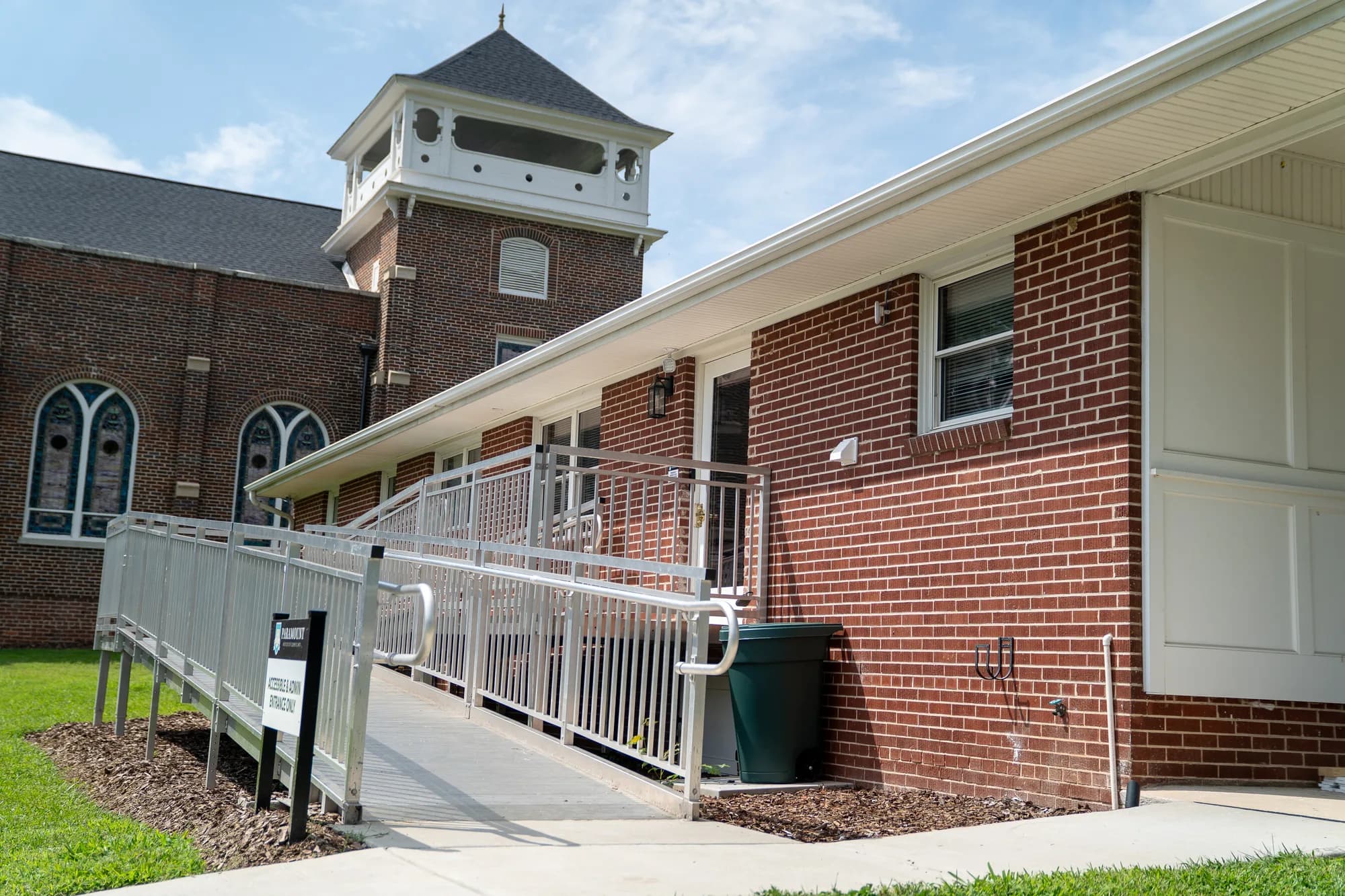 A ramp with metal railings leading to a side entrance of the brick academy building.