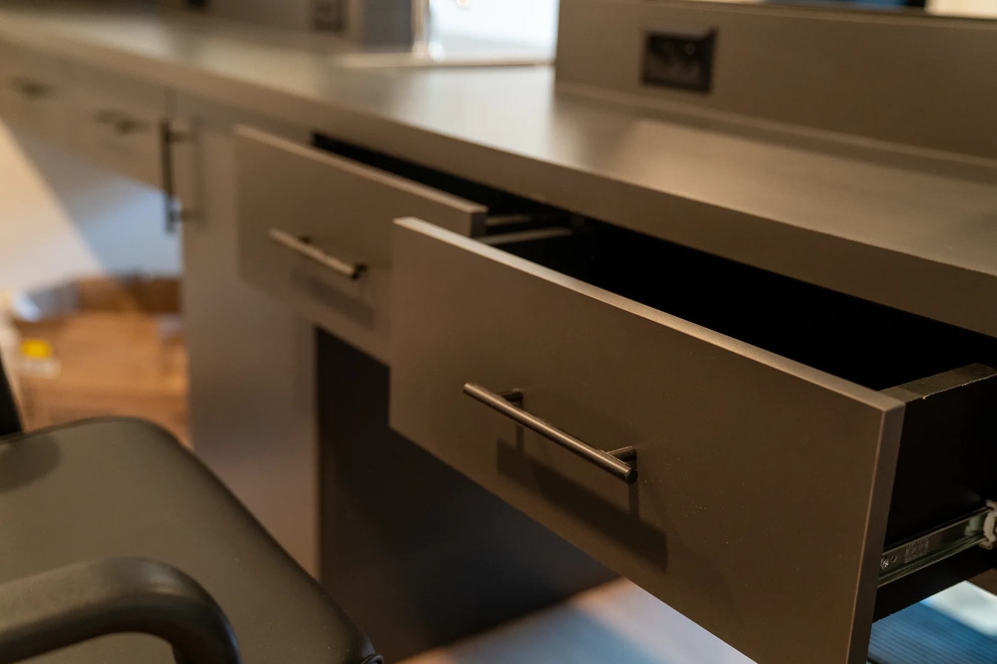 An open storage drawer beneath a gray barber workstation.